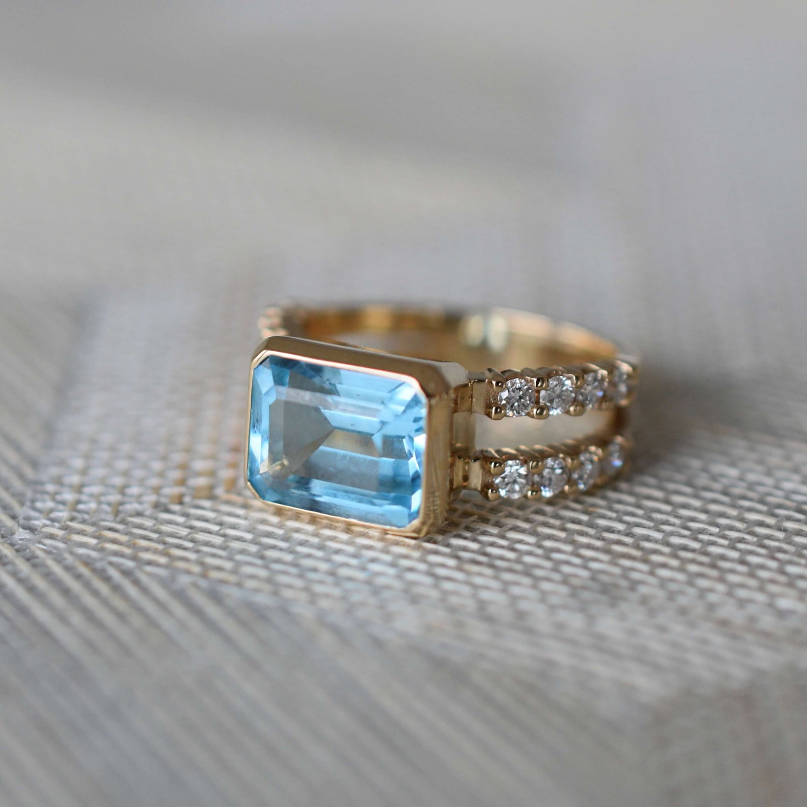 Woman wearing a 14k yellow gold Warren Horizontal Nantucket Blue Topaz Ring with Diamonds, showcasing an 8 x 10mm Nantucket Blue Topaz and 16 prong-set diamonds.