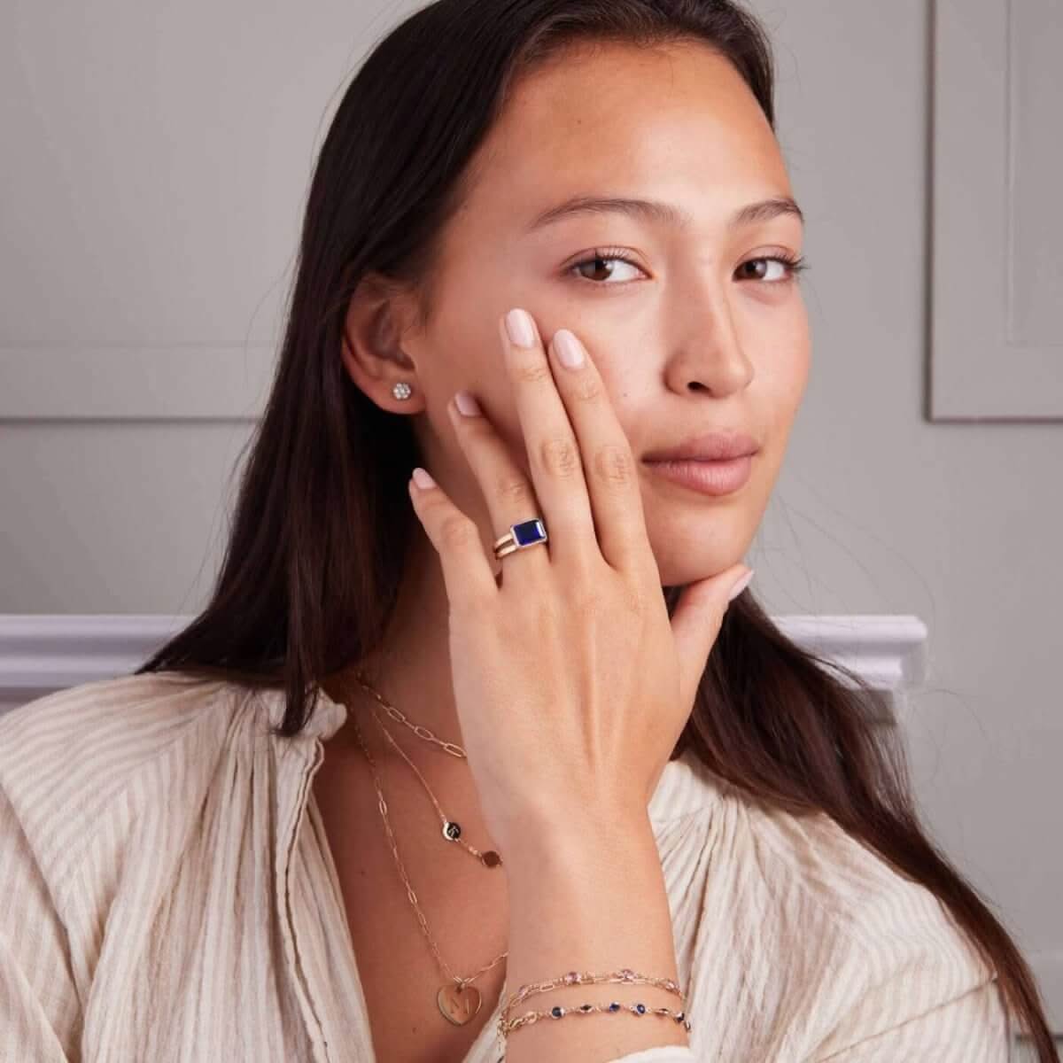Woman wearing a 14k yellow gold Warren Horizontal Sapphire Ring, showcasing an emerald-cut 8 x 10mm sapphire, hand-set horizontally in a 14k-gold bezel.