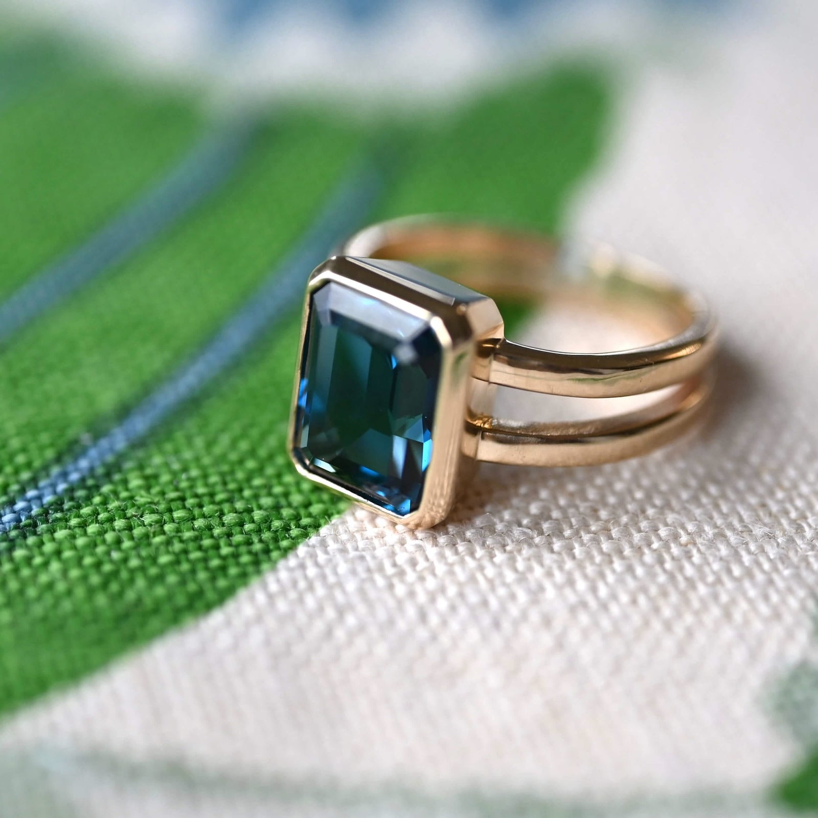 Warren Vertical Atlantic Blue Topaz Ring, featuring one 10 x 8 mm emerald cut, bezel set Atlantic Blue Topaz in 14k Yellow Gold.