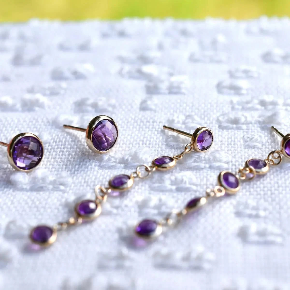 Amethyst birthstone earrings in 14k gold are shown in stud and dangle styles, emphasizing the February gemstone’s color.