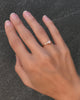 Hand wearing a Greenwich Solitaire ring featuring one 4mm faceted round cut opal and one 2.1mm diamond on a 1.5mm band.