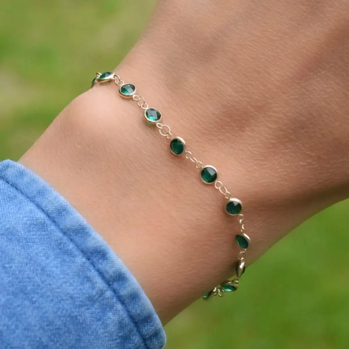 Woman with a Newport 14k yellow gold bracelet featuring 4 mm briolette cut bezel set emeralds