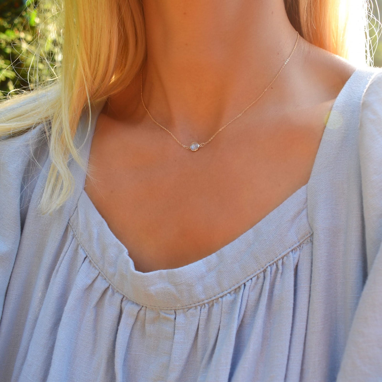 Woman wearing a Grand 14k yellow gold cable chain necklace featuring a 6 mm briolette cut bezel set moonstone