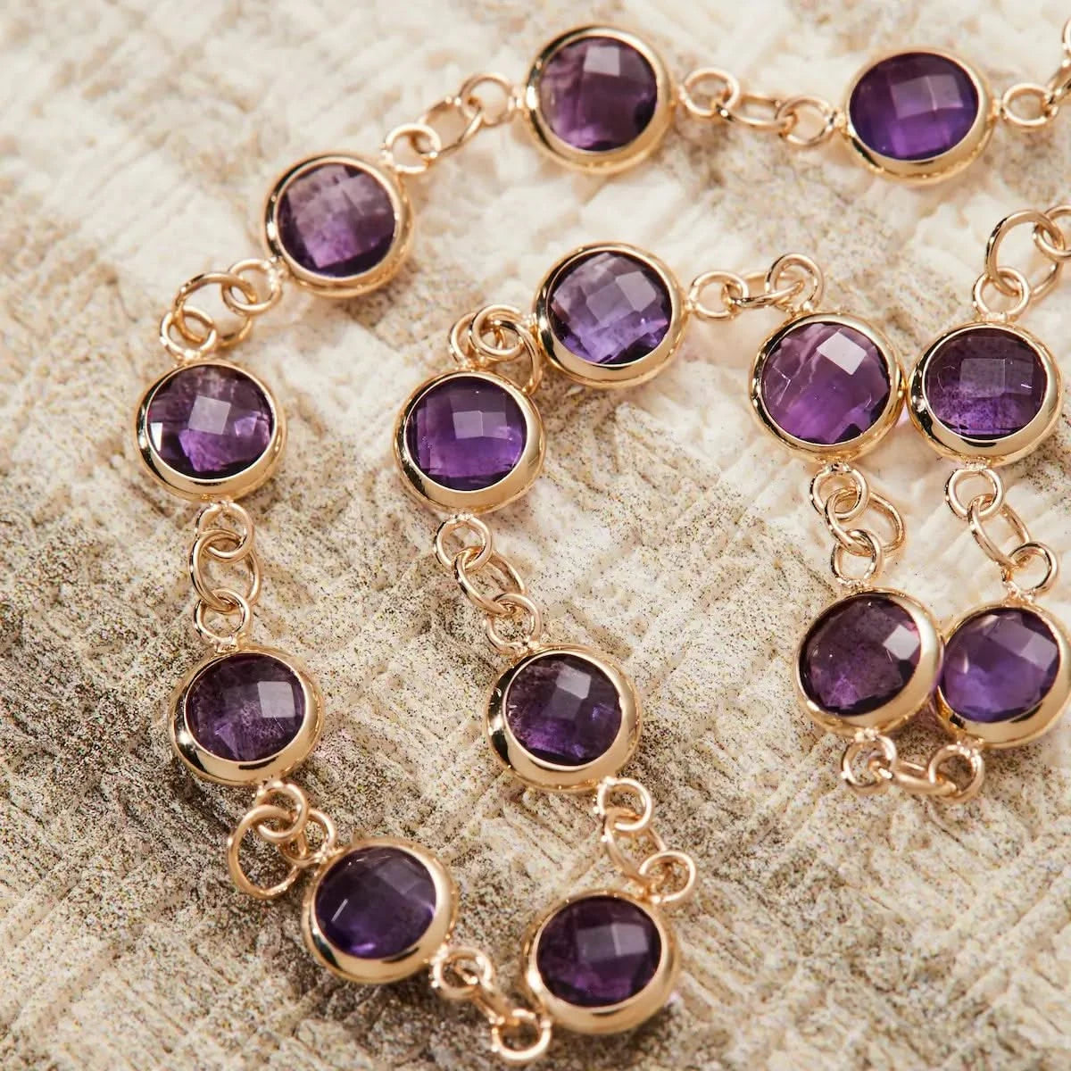 Detailed view of round briolette cut Amethysts bezel set in 14k gold links on the Newport Bracelet.