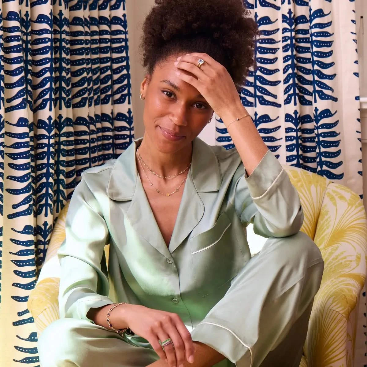 Woman wearing layered Nantucket Blue Topaz and personalized 14k gold jewelry, styled with a satin pajama set.