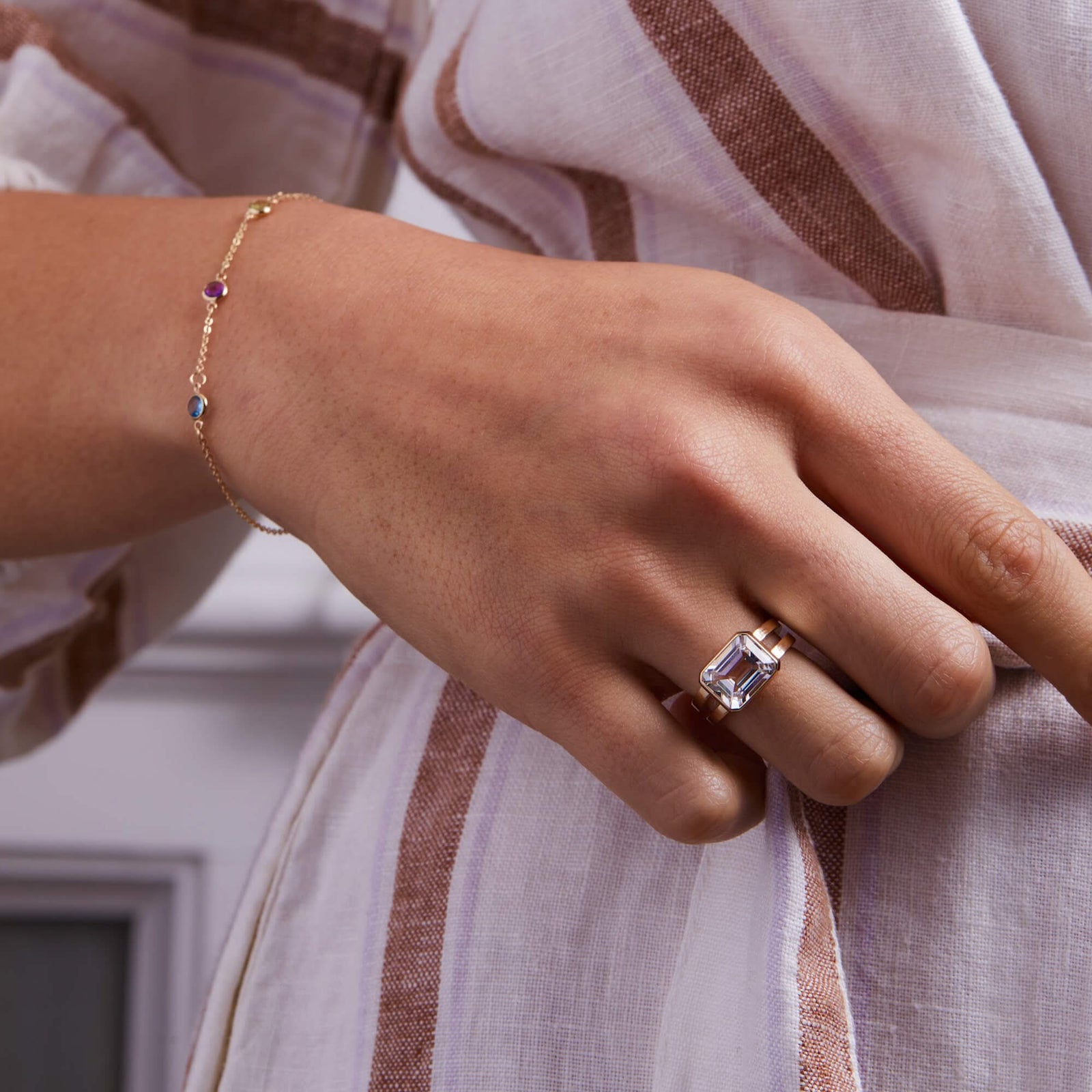 Woman adorned with a 14k yellow gold Warren Horizontal White Topaz Ring, showcasing an emerald-cut 8 x 10mm Nantucket Blue Topaz, hand-set horizontally in a 14k-gold bezel.