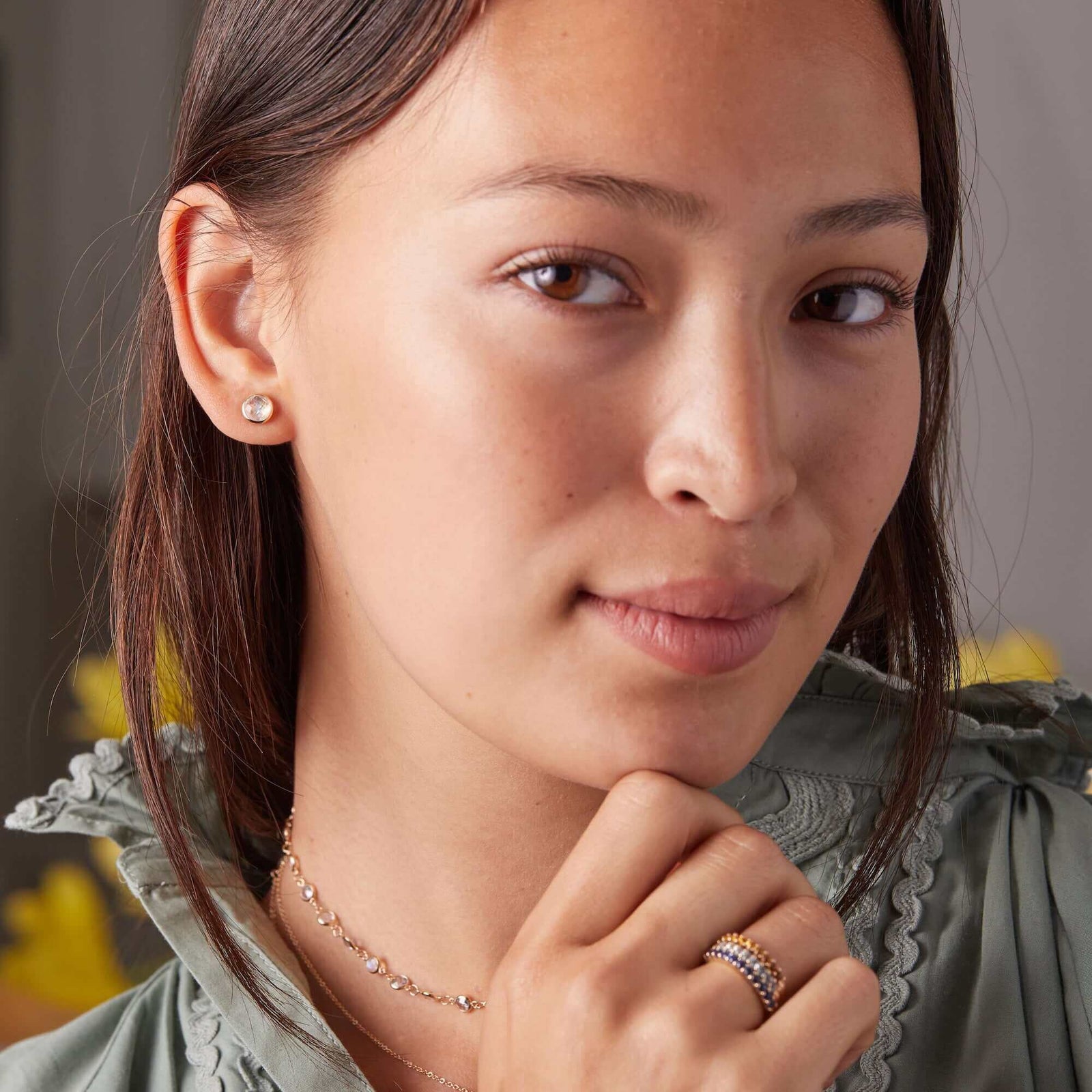 Woman adorned with a 14k yellow gold Grand stud earring featuring one 6 mm briolette cut bezel set moonstone