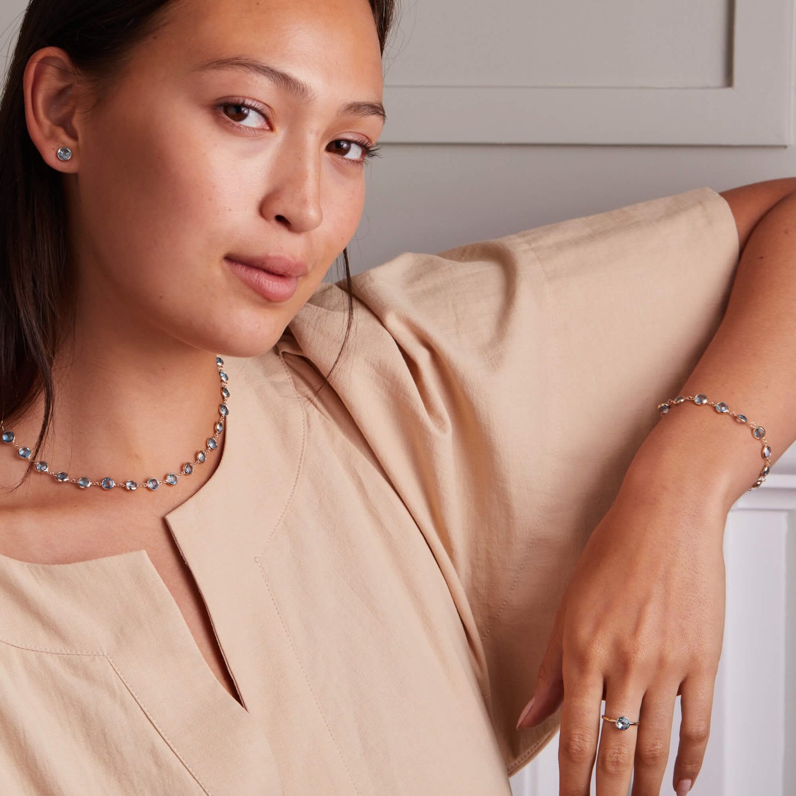 Woman wearing a brilliant Nantucket Blue Topaz Grand Ring with a 6mm round briolette-cut gemstone set in a 14k gold bezel, perfect for stacking or gifting.