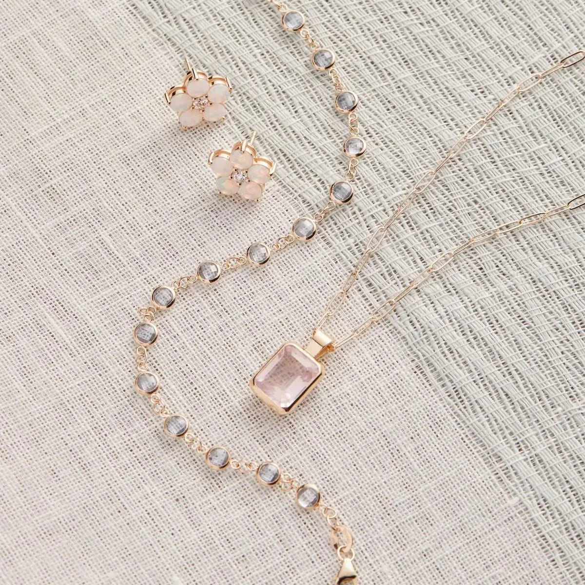 Styled flatlay of the Newport Aquamarine Bracelet in 14k gold with a matching Warren Rose Quartz Necklace and floral Greenwich Stud Earrings.