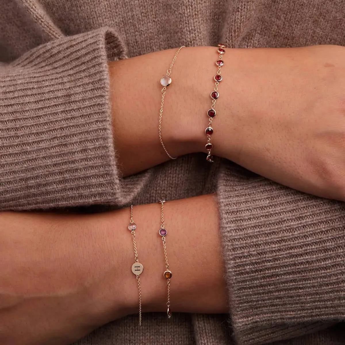 Layered 14k gold birthstone bracelets and stacking rings.