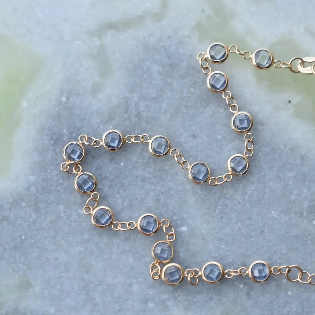 Detail shot of the Newport Aquamarine Bracelet in 14k gold on a marble surface.