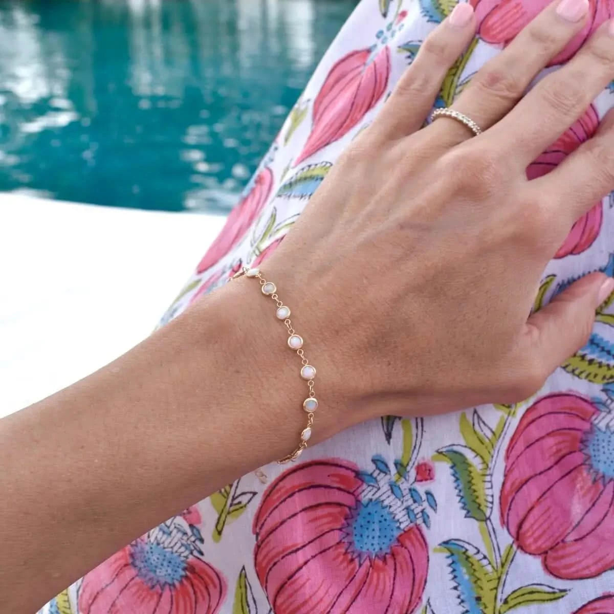 Newport Opal Bracelet on wrist with poolside setting and floral dress in background.