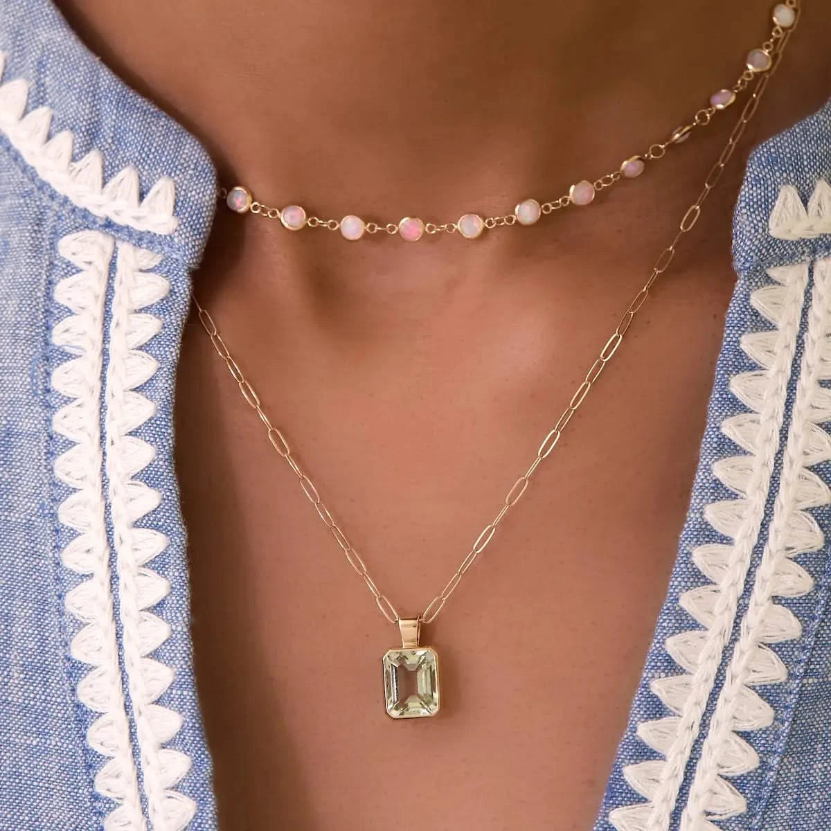 Close-up of Newport Opal Necklace paired with a green amethyst pendant necklace, styled with a scalloped blue blouse.
