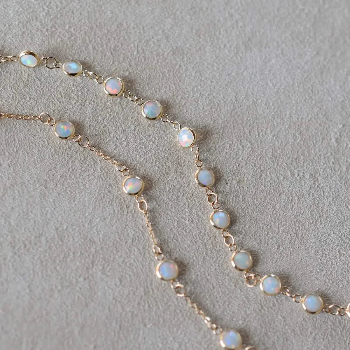 Detail of the Newport Opal Necklace chain with bezel-set opals, shown laid out on soft neutral fabric.