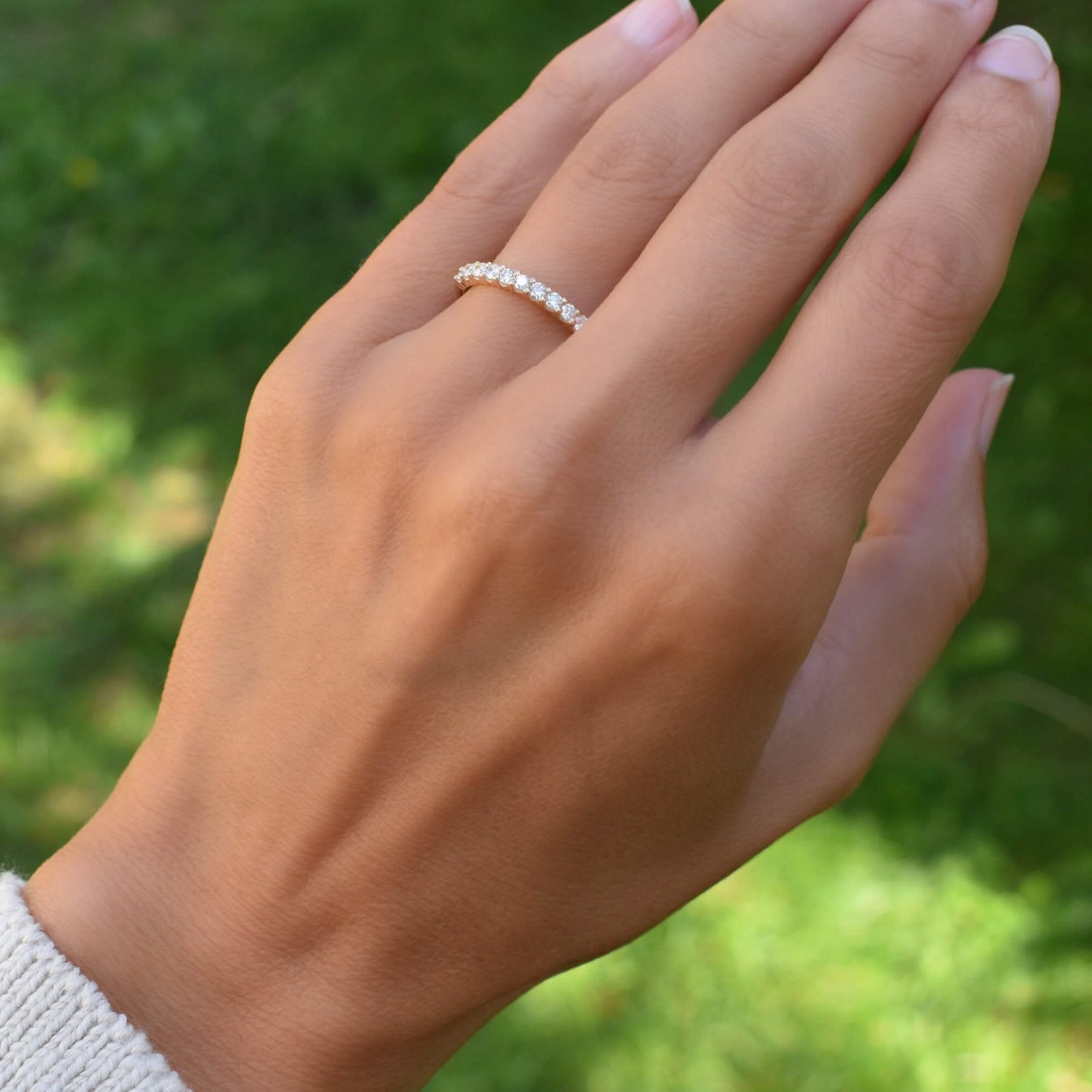 A woman adorning a Rosecliff stackable ring in 14k yellow gold, featuring eleven 2mm faceted round-cut white topaz gems prong-set on her hand.