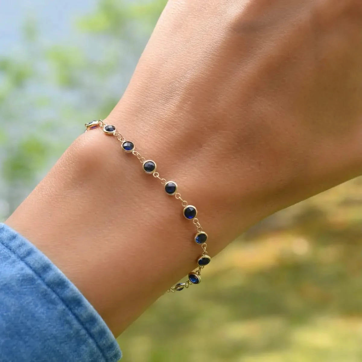 Woman with a Newport 14k yellow gold bracelet featuring 4 mm briolette cut bezel set sapphires