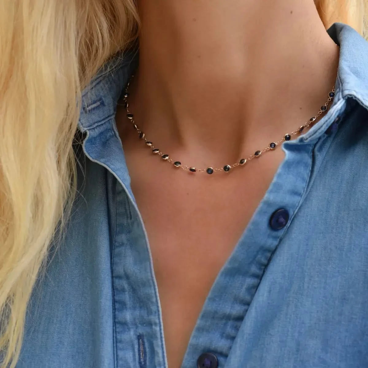 Woman wearing a Newport necklace featuring 4 mm briolette cut sapphires bezel set in 14k yellow gold