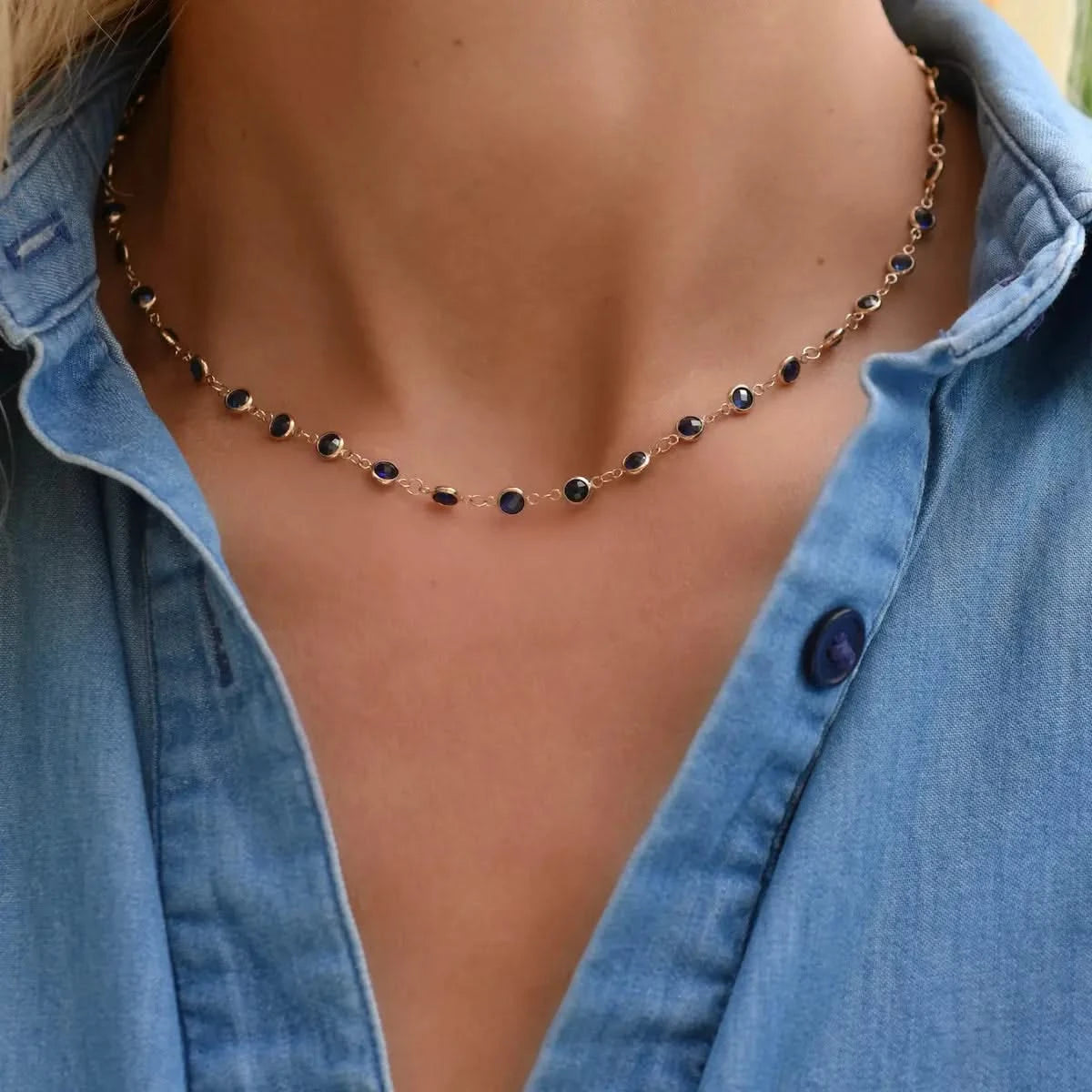 Woman wearing a Newport necklace featuring 4 mm briolette cut sapphires bezel set in 14k yellow gold