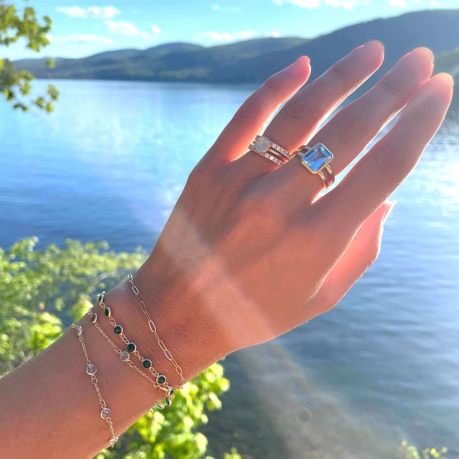 Woman wearing a Warren ring in 14k yellow gold featuring one 10 x 8 mm emerald cut bezel set Nantucket blue topaz