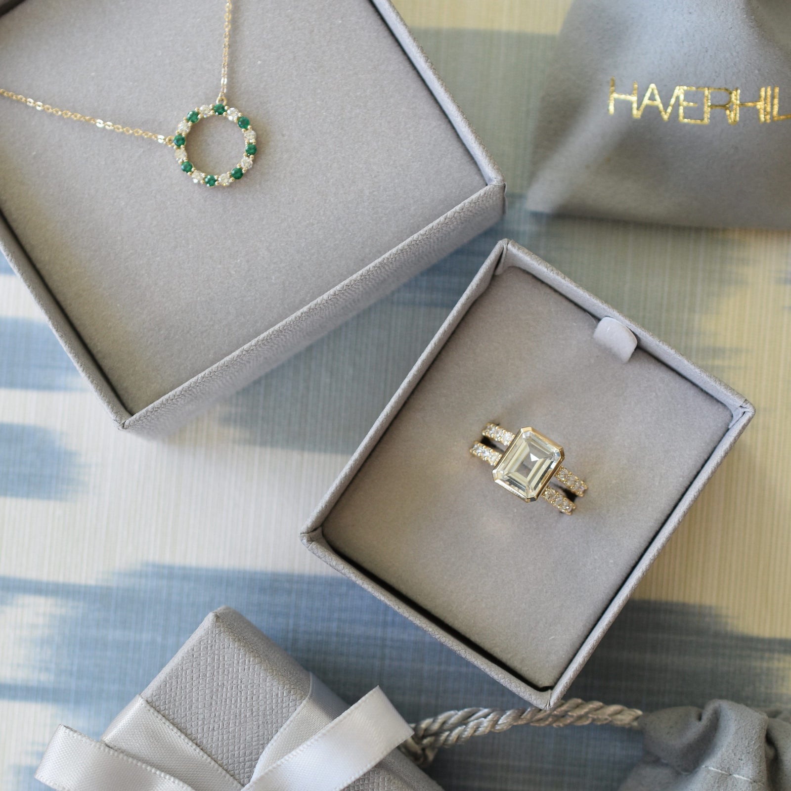 A gift box with a Warren ring with accent diamonds featuring one 10 x 8 mm emerald cut white topaz bezel set in 14k gold