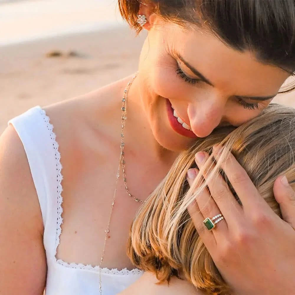 Mum showcasing a 14k yellow gold Warren Vertical Emerald Ring with Diamonds with accent diamonds featuring one 10 x 8 mm emerald cut bezel set emerald.