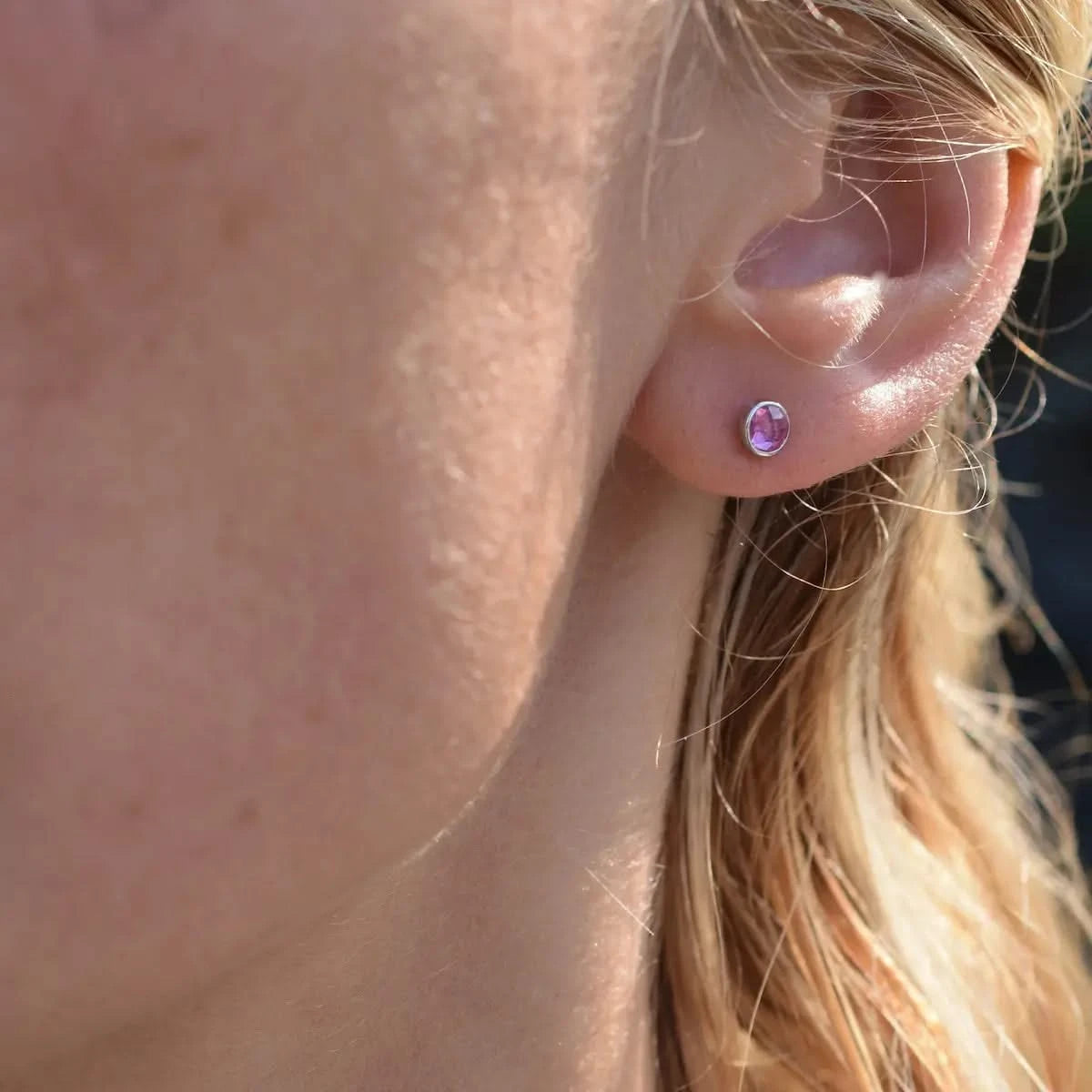 Woman wearing a Birthstone Stud Earring featuring a 4 mm briolette cut Pink Sapphire bezel set in 14k white gold