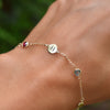 Woman wearing a 14k yellow gold Classic bracelet featuring birthstones and one 1/4” flat disc engraved with the letter H