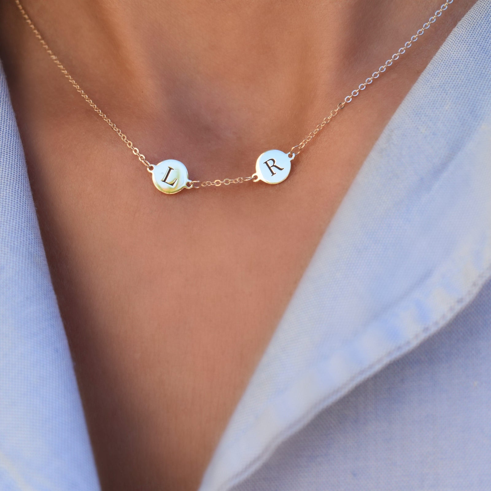 Woman with a 14k yellow gold cable chain necklace featuring two 1/4” flat discs engraved with the letters L and R