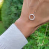 Hand holding a Rosecliff open circle necklace with sixteen 2 mm faceted round cut diamonds prong set in 14k gold