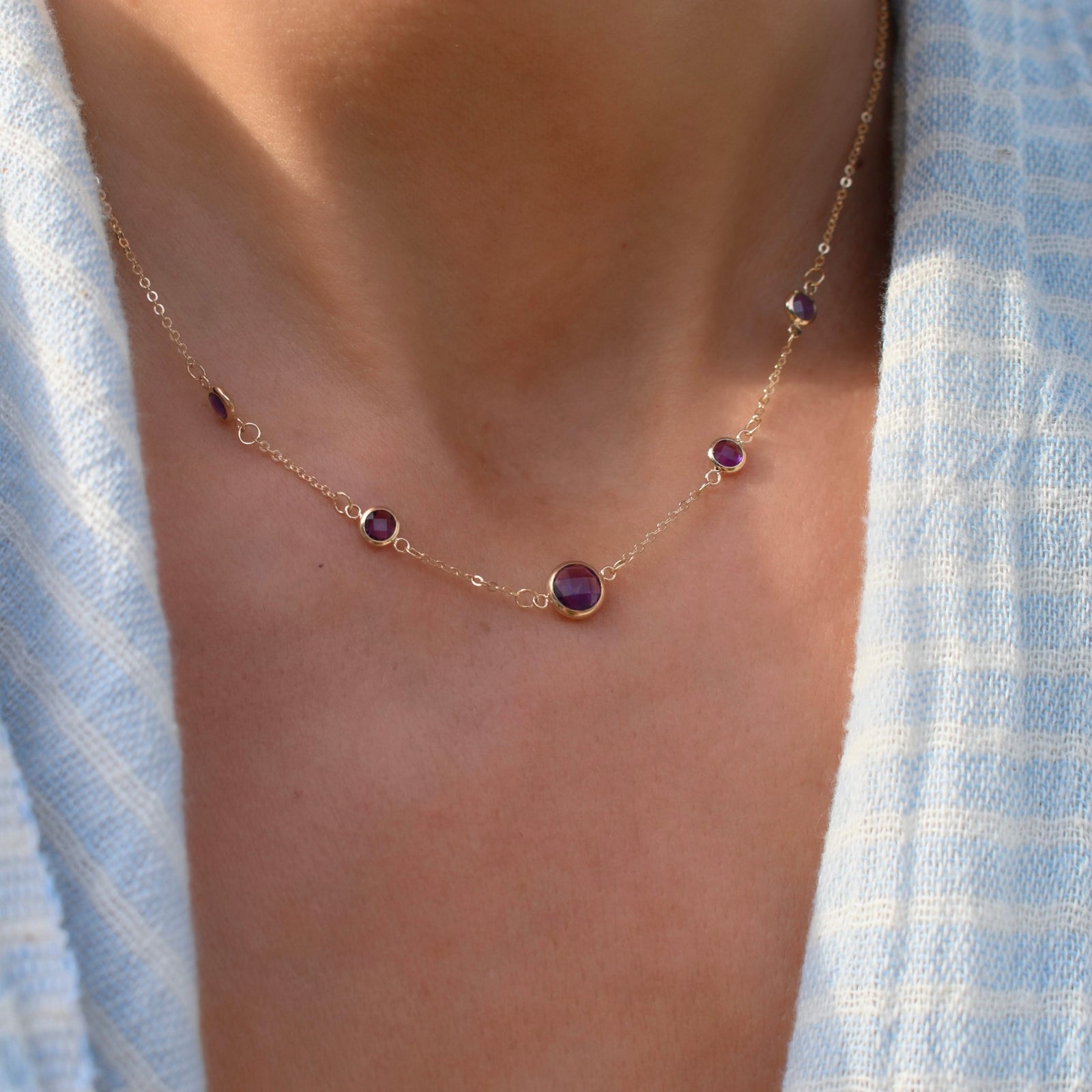 Woman with a Grand & Classic necklace featuring one 6 mm and four 4 mm Amethysts bezel set in 14k yellow gold