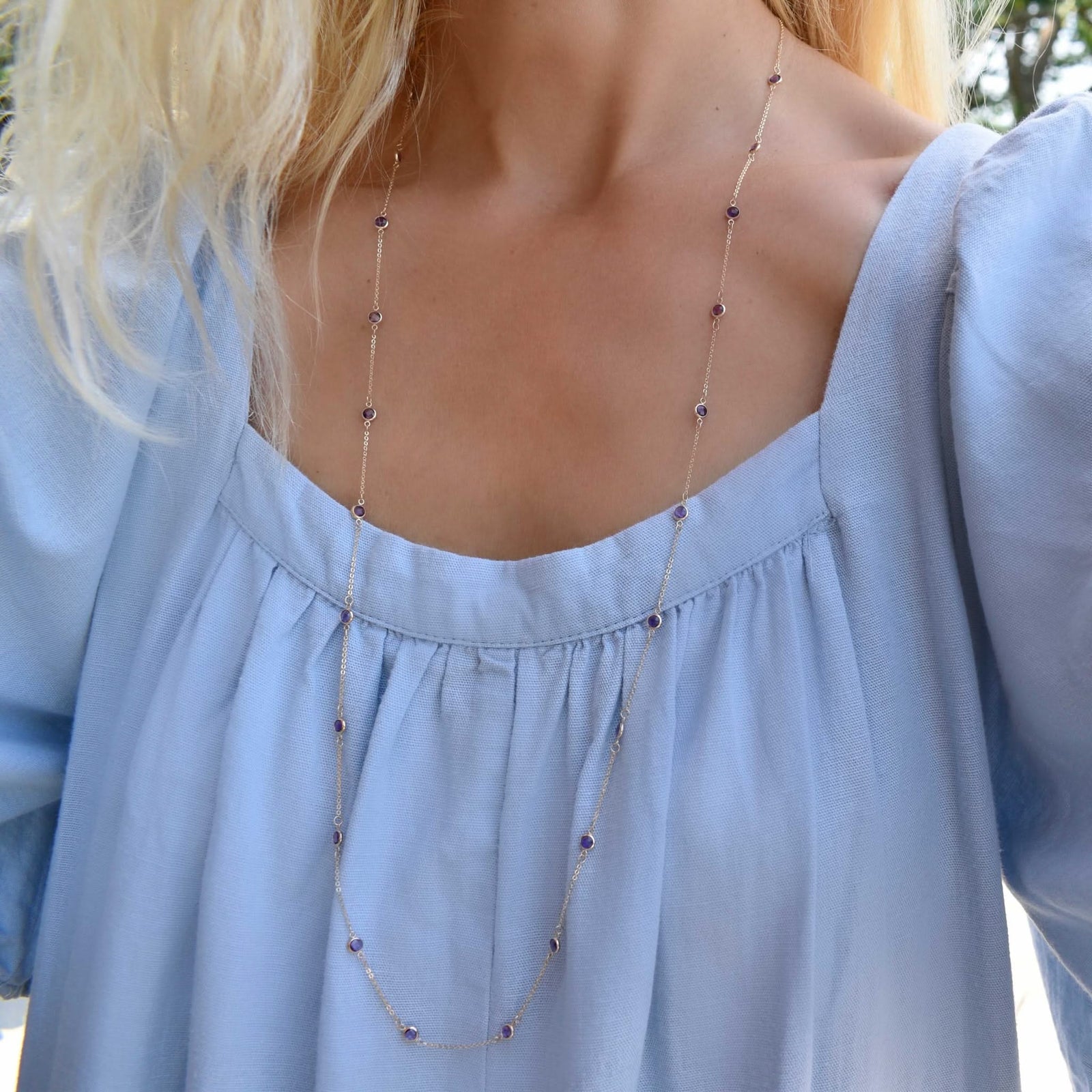 Woman wearing a Bayberry Birthstone Wrap necklace featuring 4 mm briolette cut amethysts bezel set in 14k yellow gold