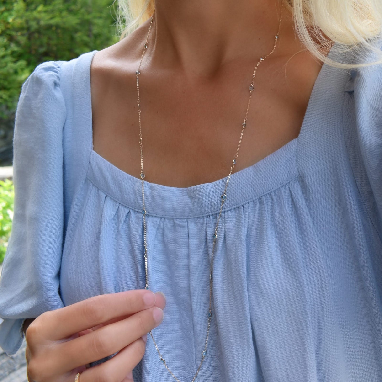 Woman with a Bayberry Birthstone Wrap necklace featuring 4 mm briolette cut Nantucket blue topaz bezel set in 14k gold