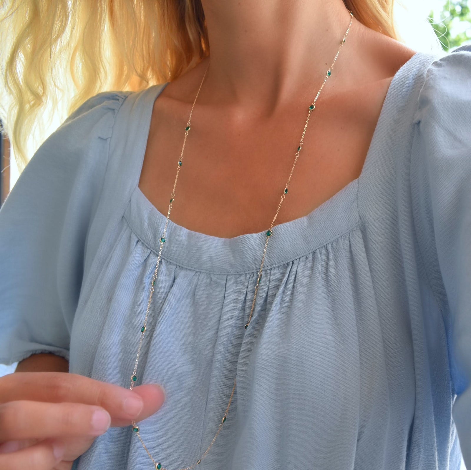 Woman wearing a Bayberry Birthstone Wrap necklace featuring 4 mm briolette cut emeralds bezel set in 14k yellow gold