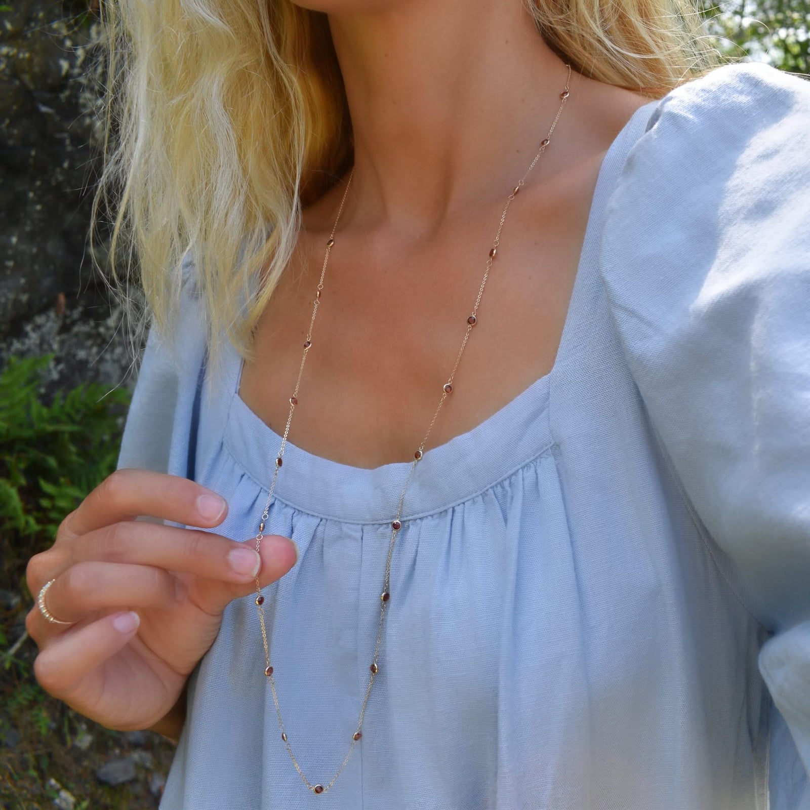 Woman wearing a Bayberry Birthstone Wrap necklace featuring 4 mm briolette cut garnets bezel set in 14k gold