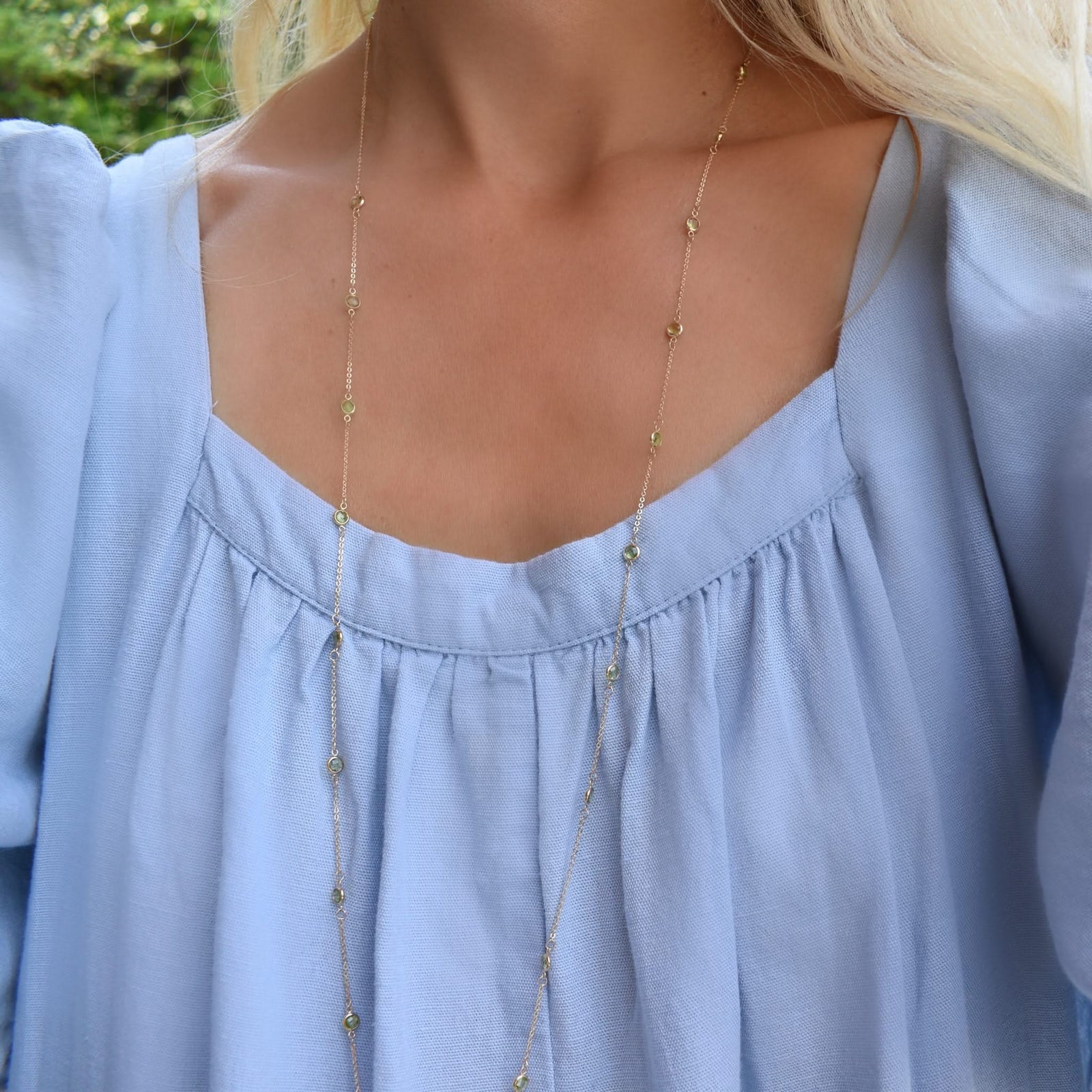 Woman wearing a Bayberry Birthstone Wrap necklace featuring 4 mm briolette cut peridots bezel set in 14k gold