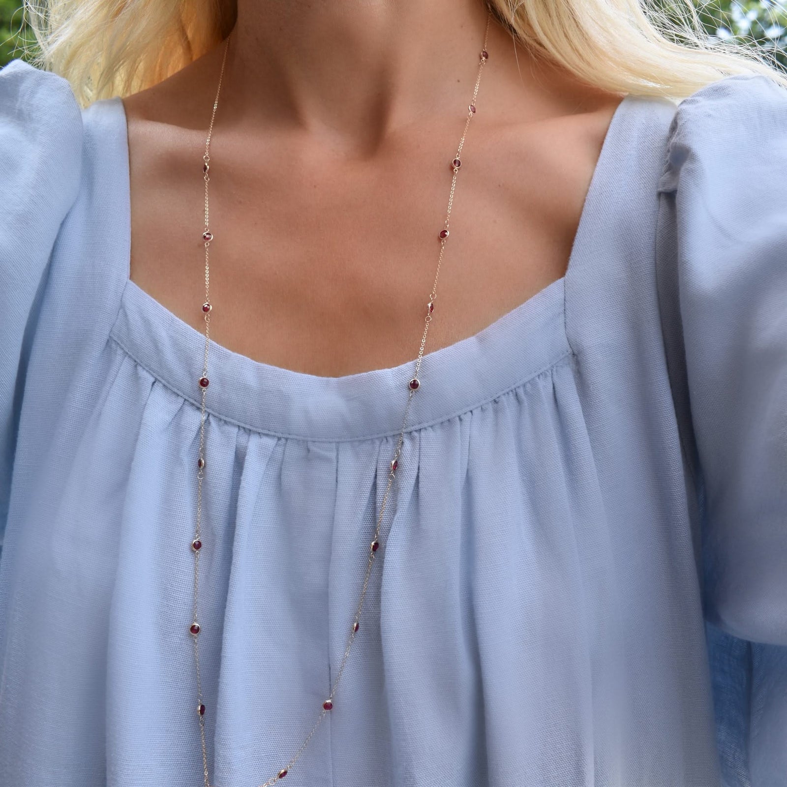 Woman wearing a Bayberry Birthstone Wrap necklace featuring 4 mm briolette cut rubies bezel set in 14k yellow gold