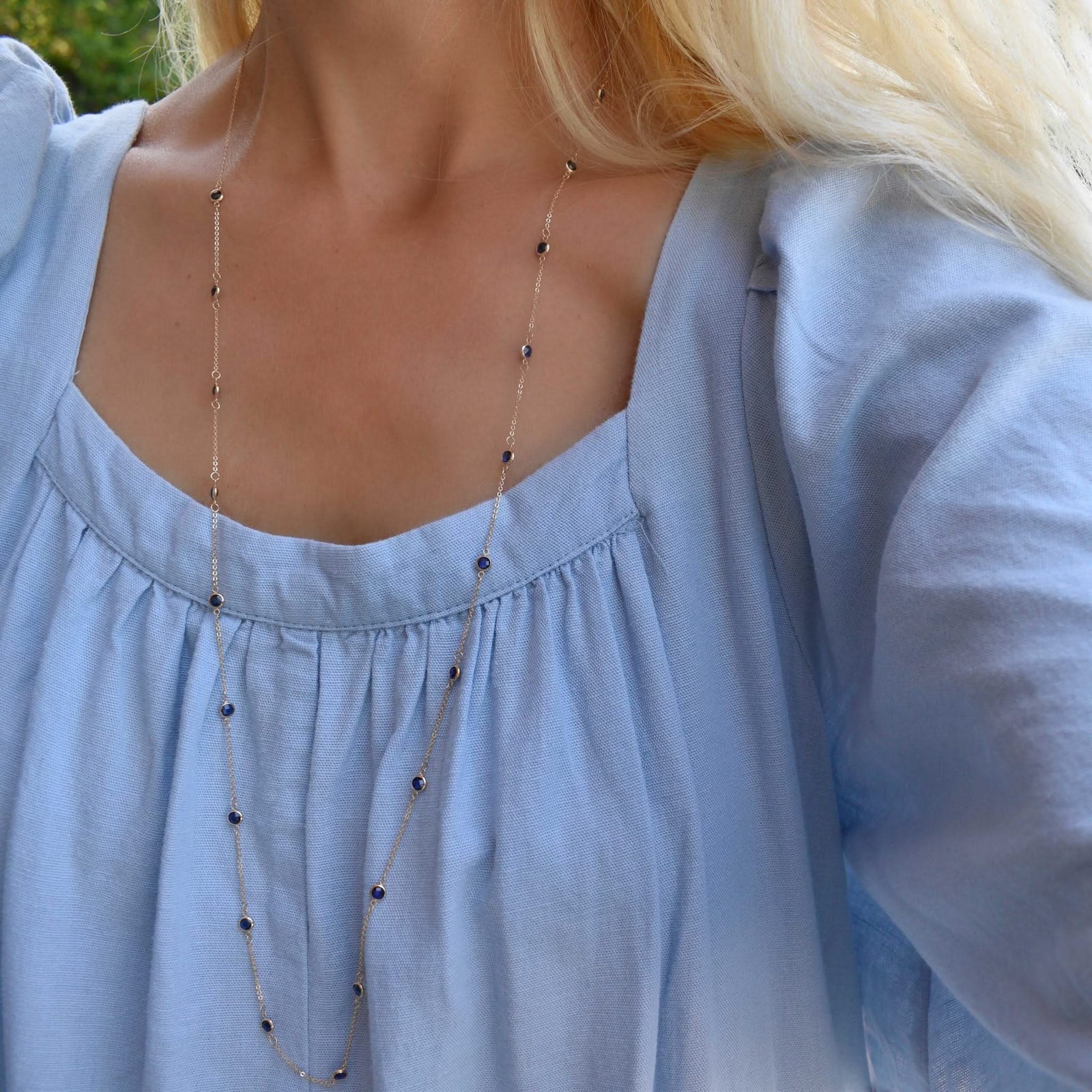 Woman wearing a Bayberry Birthstone Wrap necklace featuring 4 mm briolette cut sapphires bezel set in 14k gold