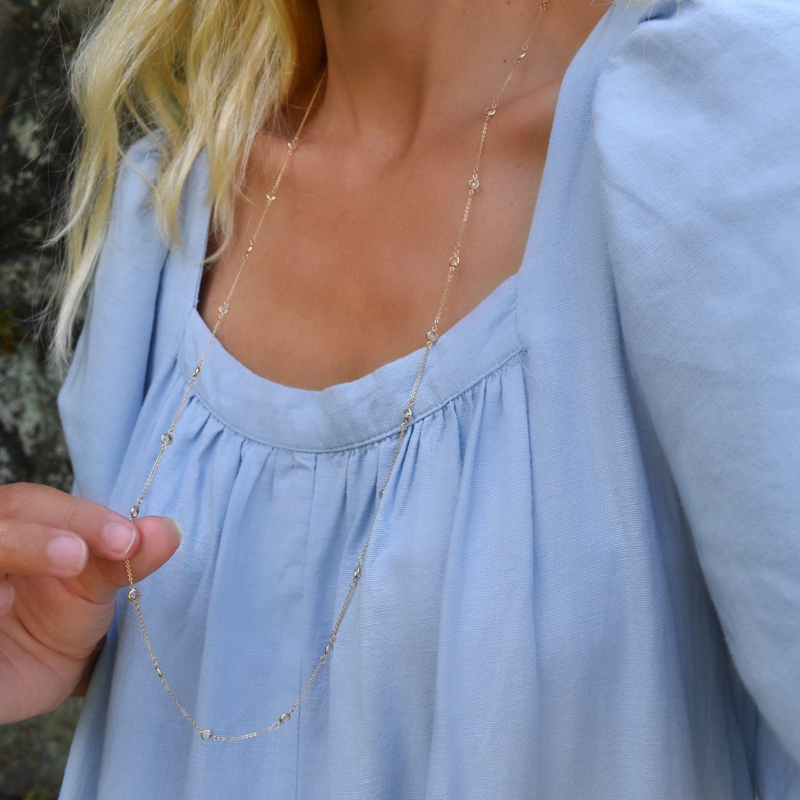 Woman wearing a Bayberry Birthstone Wrap necklace featuring 4 mm briolette cut white topaz bezel set in 14k yellow gold