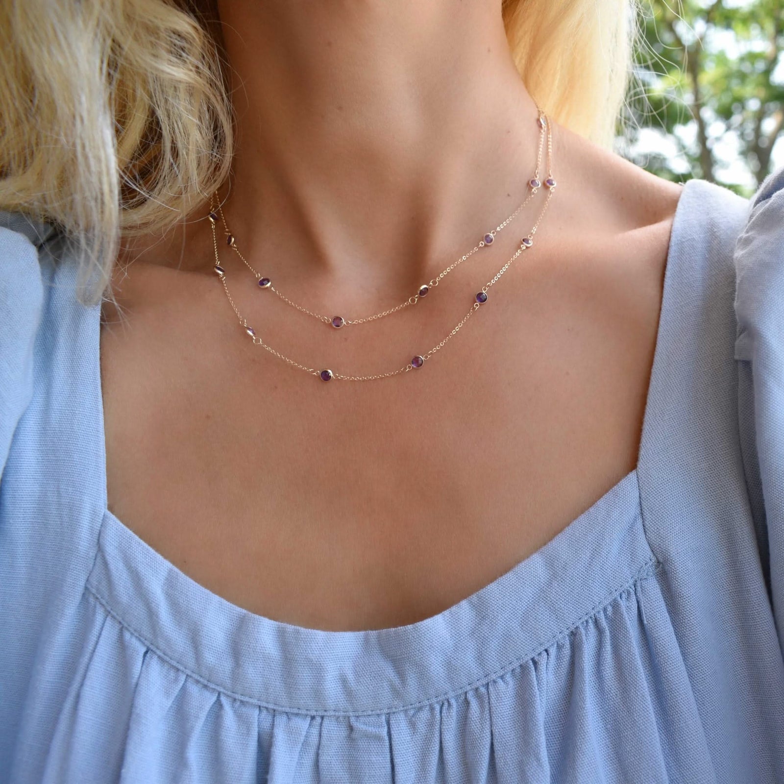 Woman wearing a Bayberry Birthstone Wrap necklace featuring 4 mm briolette cut amethysts bezel set in 14k gold