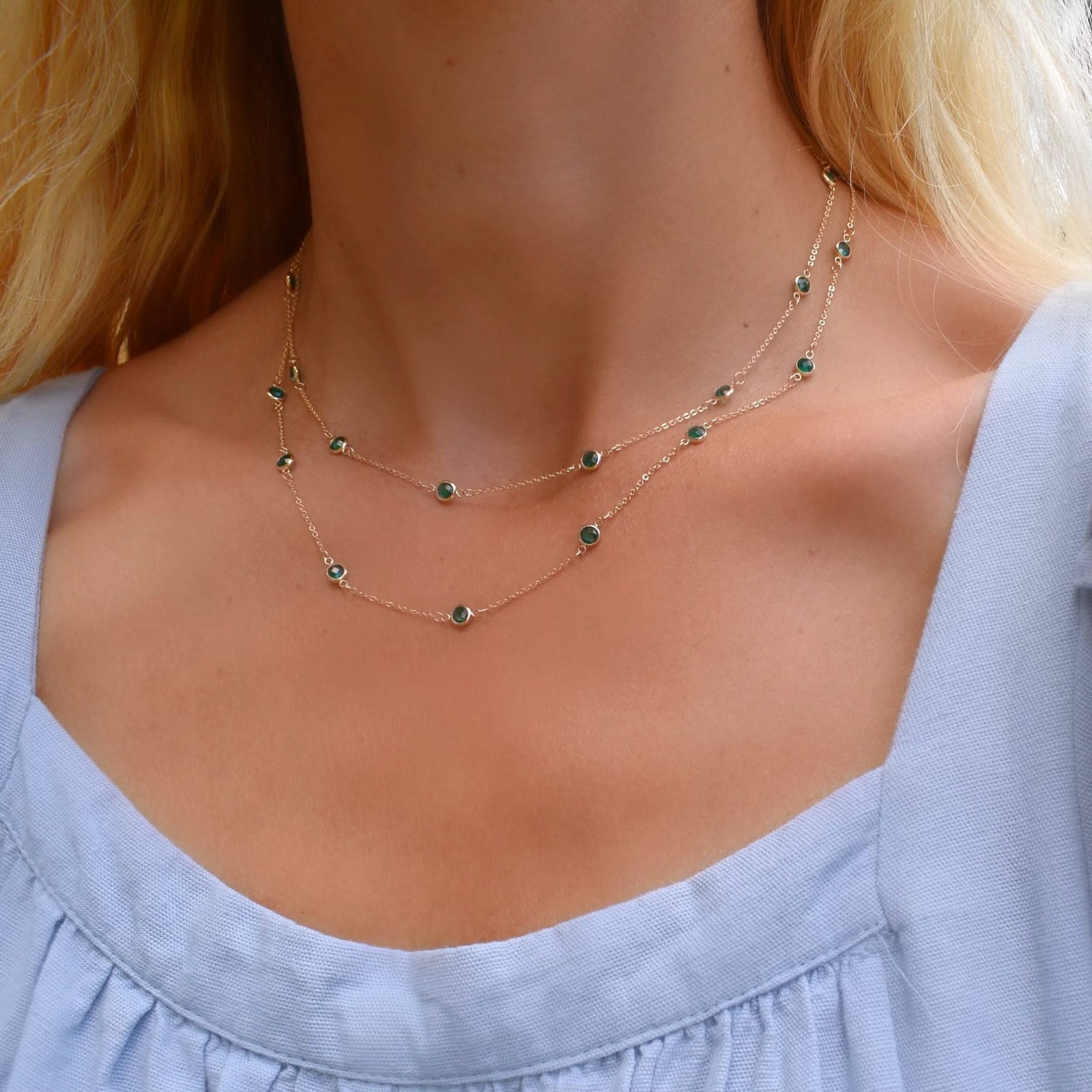 Woman wearing a Bayberry Birthstone Wrap necklace featuring 4 mm briolette cut emeralds bezel set in 14k gold