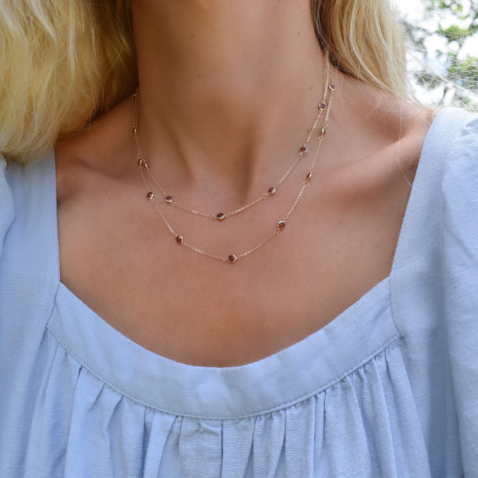 Woman wearing a Bayberry Birthstone Wrap necklace featuring 4 mm briolette cut garnets bezel set in 14k yellow gold