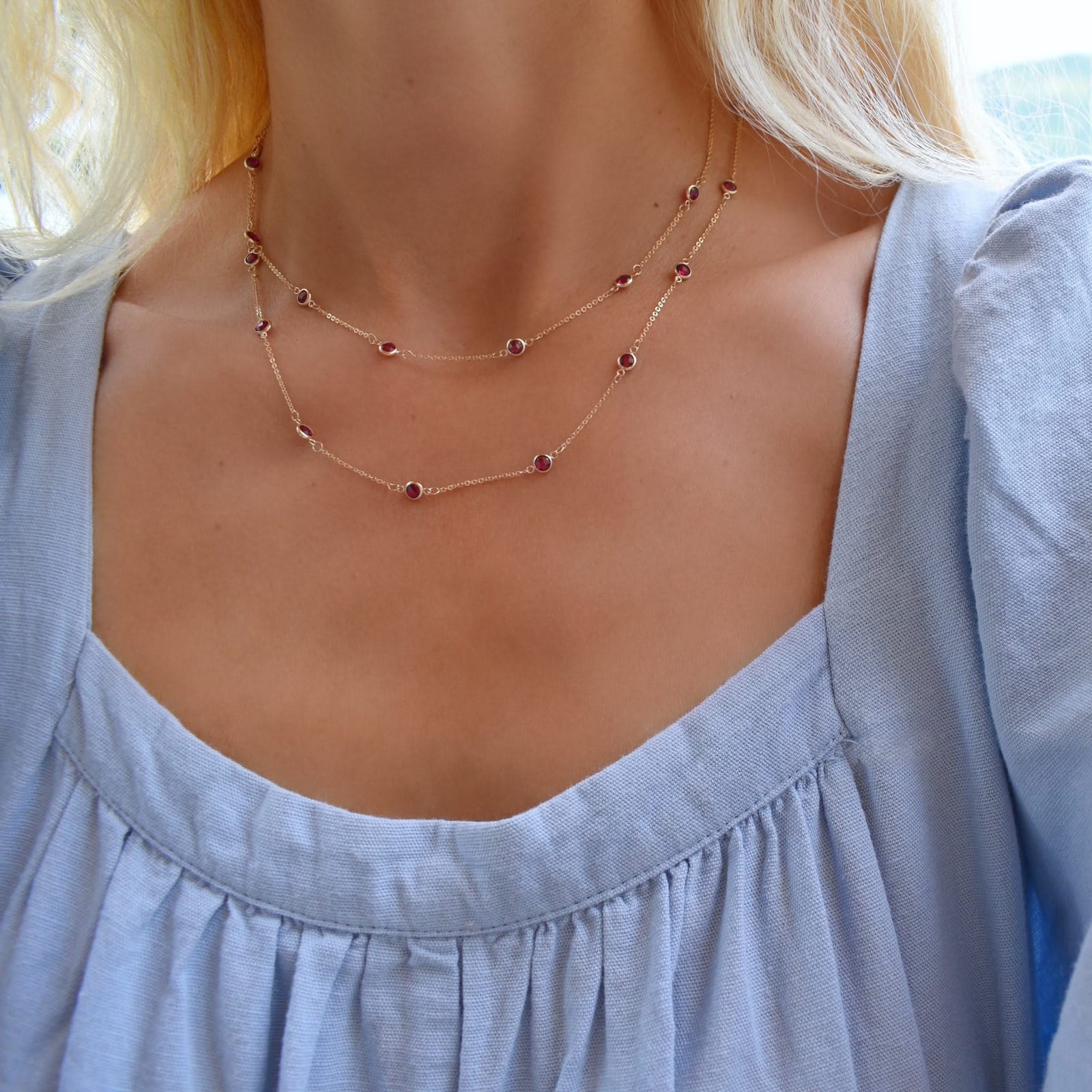 Woman with a Bayberry Birthstone Wrap necklace featuring 4 mm briolette cut rubies bezel set in 14k yellow gold