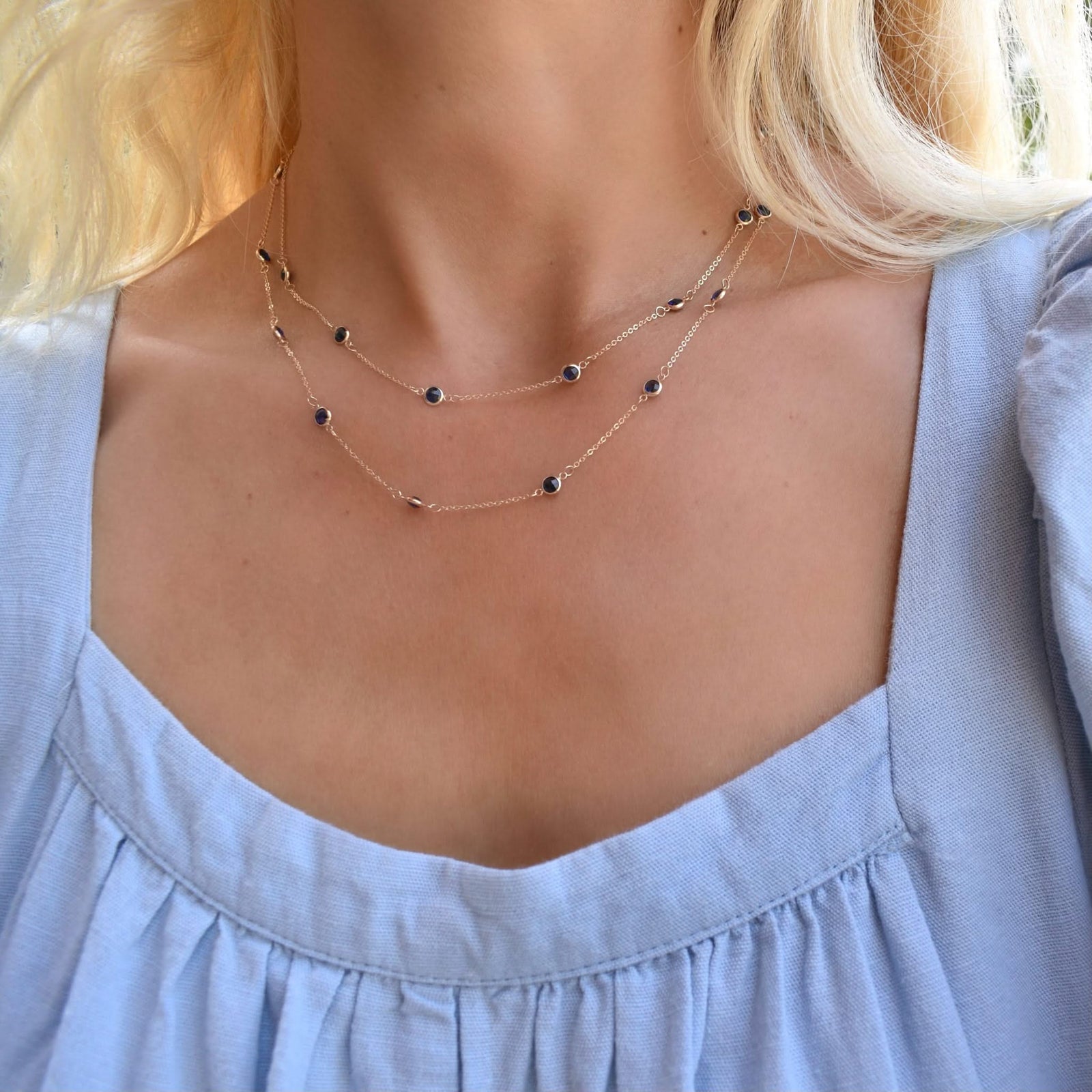 Woman wearing a Bayberry Birthstone Wrap necklace featuring 4 mm briolette cut sapphires bezel set in 14k yellow gold