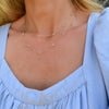 Woman wearing a Bayberry Birthstone Wrap necklace featuring 4 mm briolette cut white topaz bezel set in 14k yellow gold