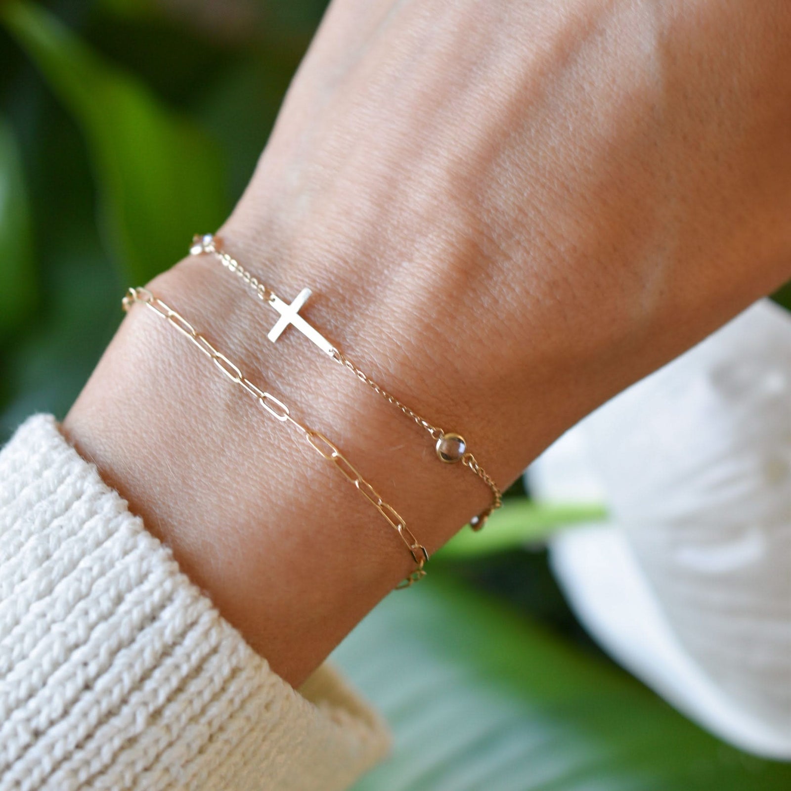 Woman wearing two bracelets including a 14k yellow gold Classic bracelet featuring birthstones and a 1/2" cutout cross