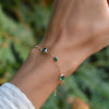 Woman with a Bayberry Grand & Classic cable chain bracelet in 14k gold featuring seven alternating 4 mm and 6 mm emeralds