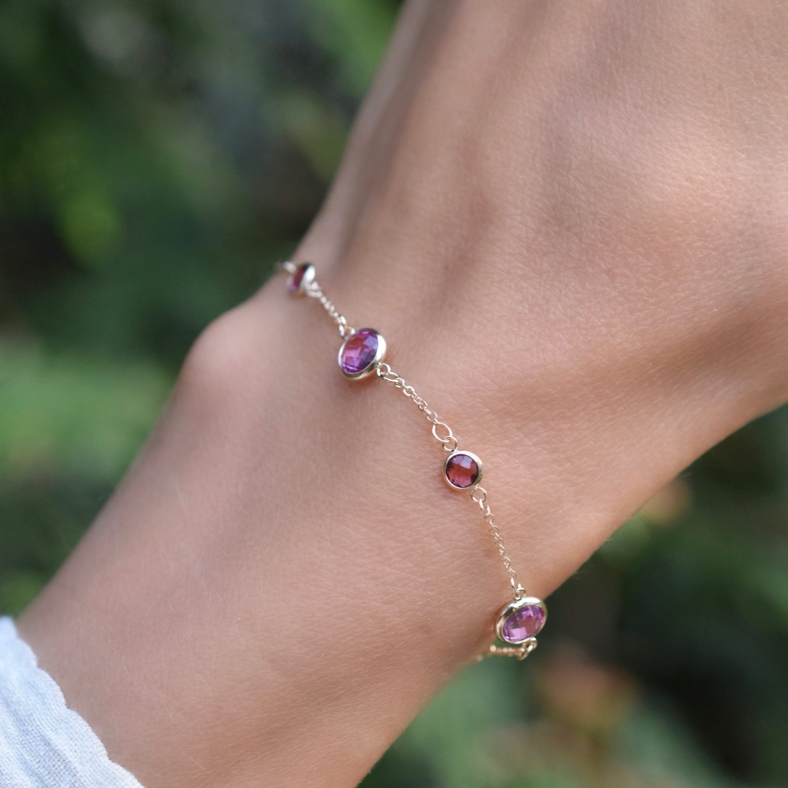 Hand with a Bayberry Grand & Classic cable chain bracelet in 14k gold with 4 mm & 6 mm pink tourmalines & pink sapphires
