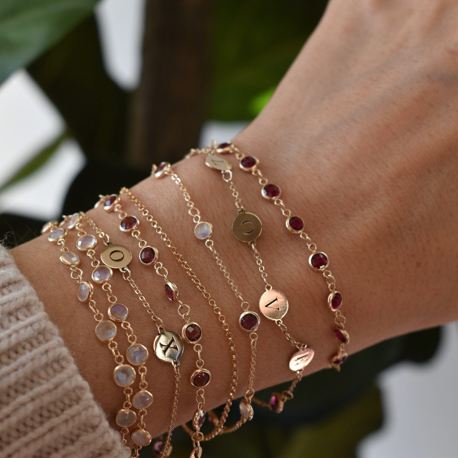 Woman wearing several bracelets including two 14k gold bracelets featuring four 1/4” flat engraved letter discs