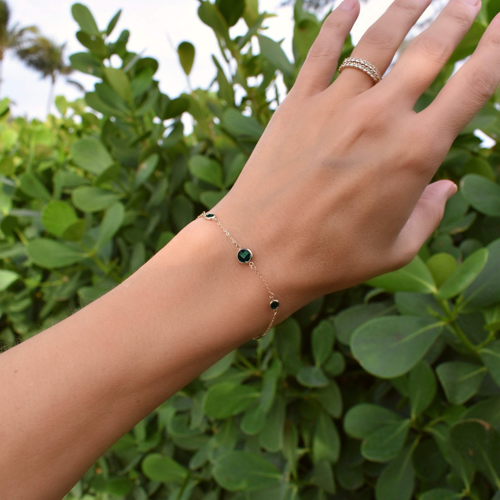 Woman wearing a Grand & Classic bracelet featuring one 6 mm and four 4 mm briolette Emeralds bezel set in 14k yellow gold