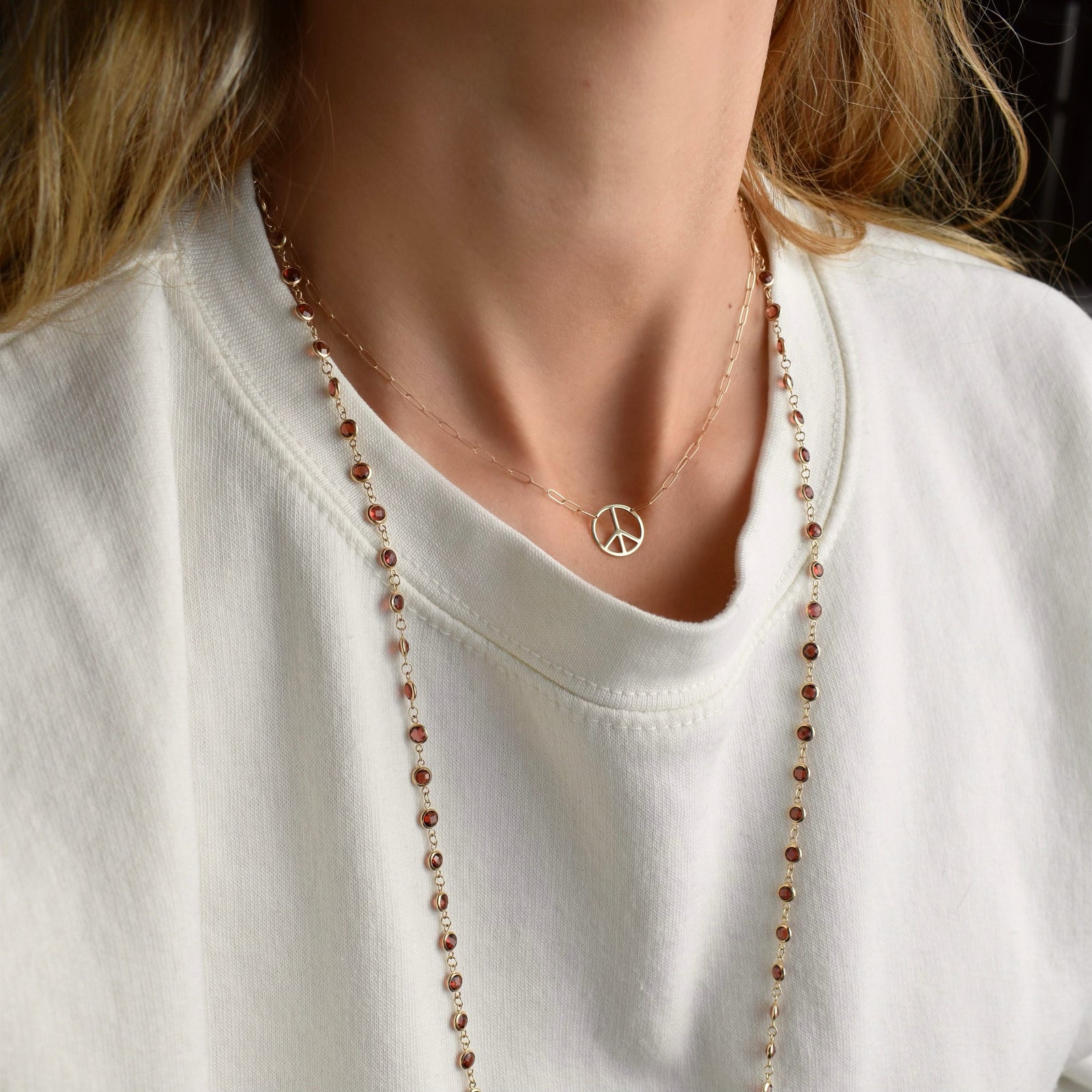 Woman with an Adelaide Mini necklace featuring one 1/2” cutout Peace Sign in 14k yellow gold